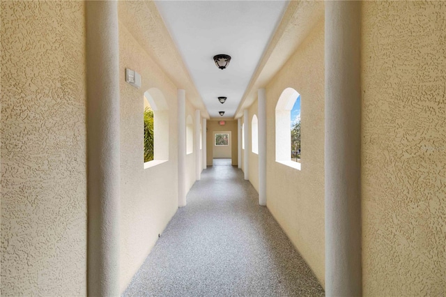 hall featuring a wealth of natural light and a textured wall