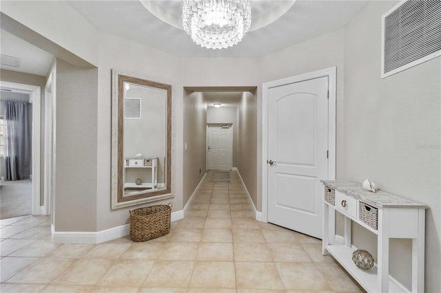 corridor with baseboards, visible vents, a chandelier, and light tile patterned flooring