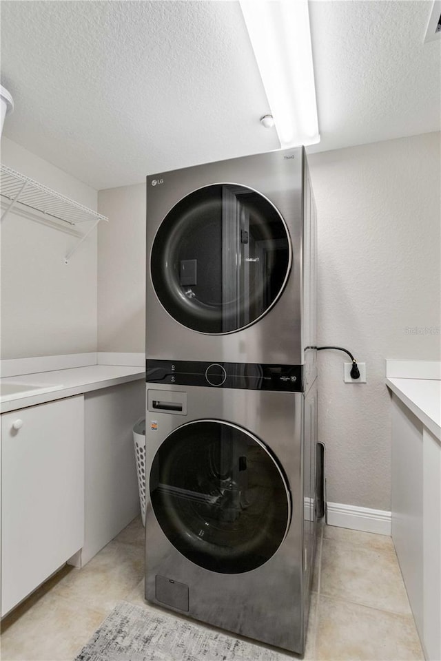 clothes washing area featuring laundry area, stacked washer and dryer, and a textured ceiling