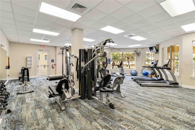 gym with a paneled ceiling, carpet, visible vents, and baseboards