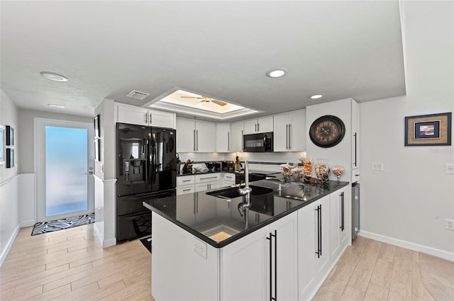 kitchen featuring black appliances, light wood-type flooring, a peninsula, and white cabinets