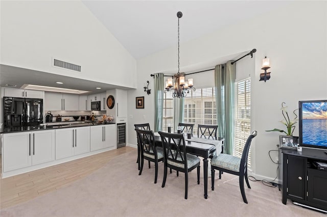 dining space with wine cooler, high vaulted ceiling, visible vents, a chandelier, and baseboards