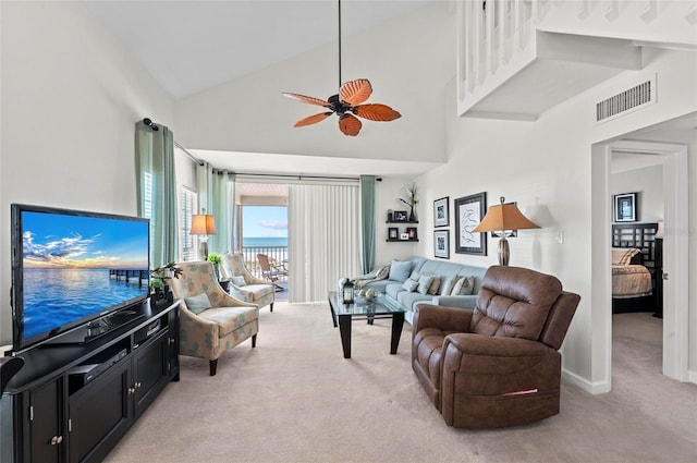 living area with ceiling fan, high vaulted ceiling, light colored carpet, visible vents, and baseboards