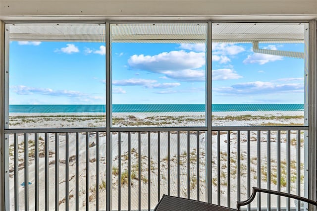 unfurnished sunroom featuring a water view and a view of the beach