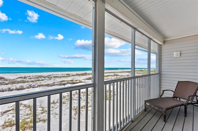 sunroom featuring a view of the beach and a water view