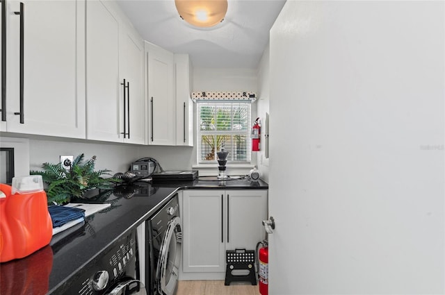 laundry area with light wood-type flooring, washing machine and dryer, and cabinet space