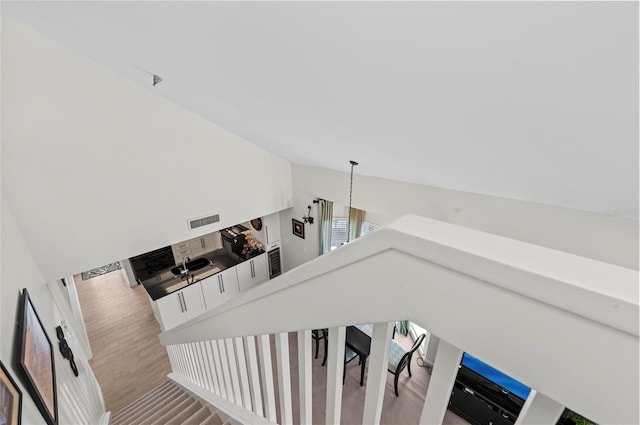 stairway with lofted ceiling, visible vents, and wood finished floors