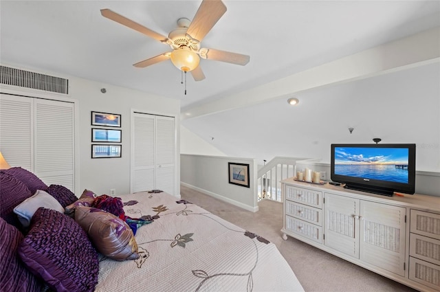 bedroom with light colored carpet, a ceiling fan, baseboards, visible vents, and two closets