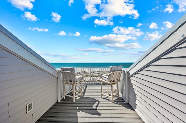 wooden terrace with a water view and a view of the beach