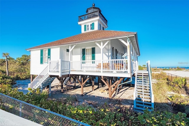 view of front of home with roof with shingles, a porch, and stairway