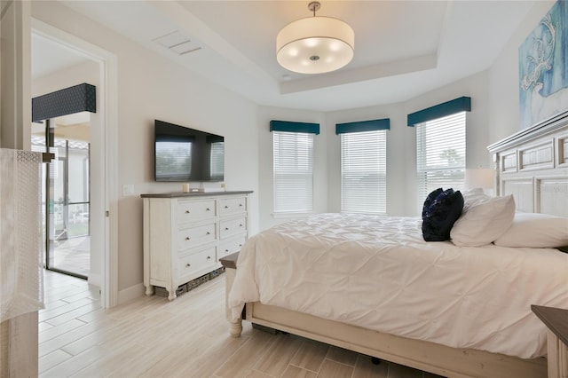 bedroom featuring wood tiled floor, baseboards, and a raised ceiling