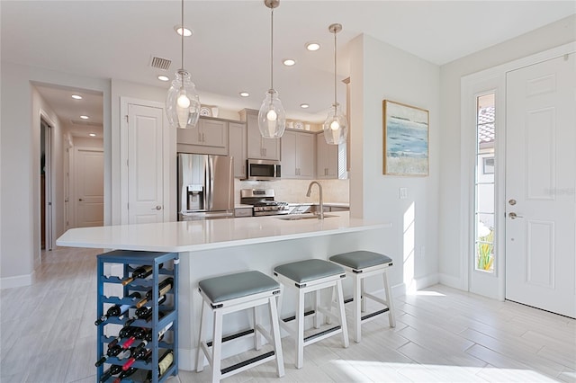 kitchen featuring stainless steel appliances, light countertops, hanging light fixtures, visible vents, and gray cabinetry