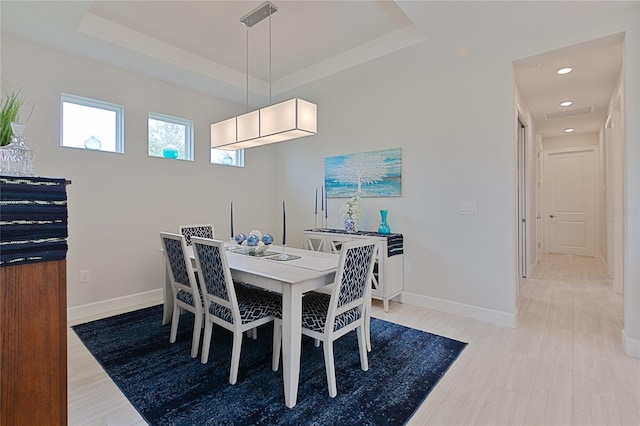 dining area with recessed lighting, a raised ceiling, light wood-style flooring, and baseboards