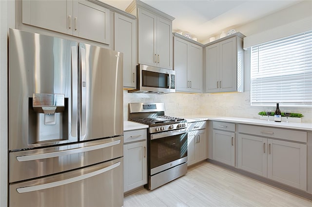 kitchen featuring appliances with stainless steel finishes, light countertops, gray cabinetry, and tasteful backsplash