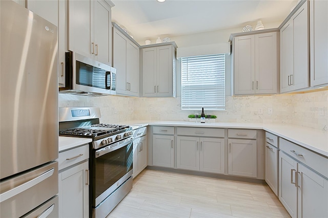 kitchen with appliances with stainless steel finishes, light countertops, and gray cabinetry