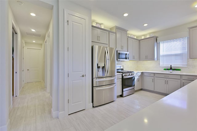 kitchen featuring recessed lighting, light countertops, appliances with stainless steel finishes, gray cabinets, and backsplash