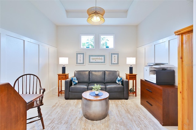 living area featuring light wood-style floors, a tray ceiling, and a towering ceiling