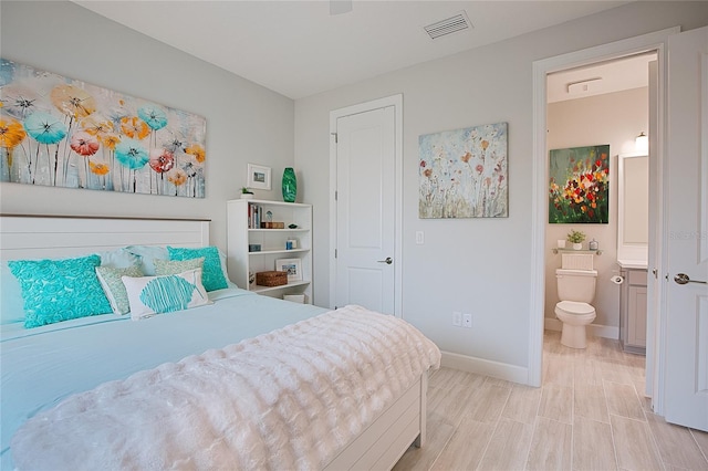 bedroom with visible vents, baseboards, and ensuite bathroom