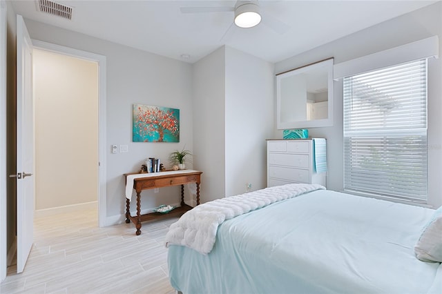 bedroom with light wood-style floors, visible vents, baseboards, and a ceiling fan