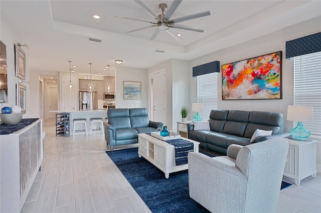 living room with ceiling fan, a raised ceiling, visible vents, and recessed lighting