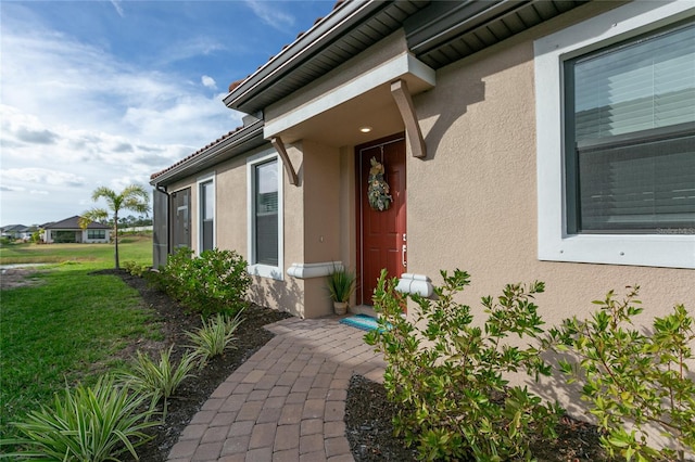 doorway to property featuring a yard and stucco siding