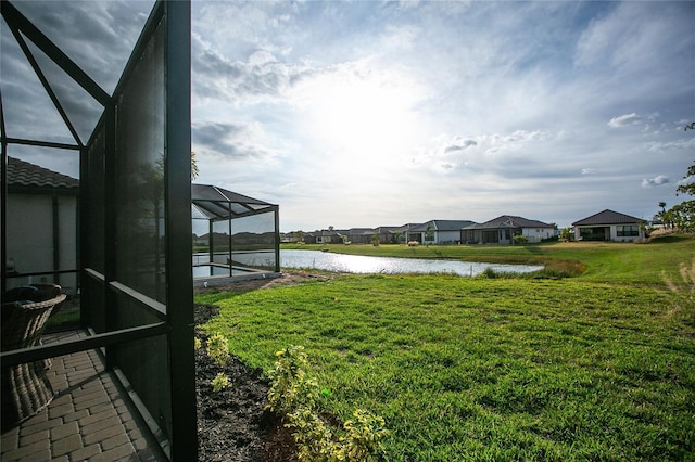 view of yard with a pool, a residential view, glass enclosure, and a water view