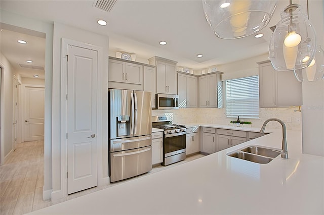 kitchen featuring light countertops, hanging light fixtures, visible vents, appliances with stainless steel finishes, and a sink