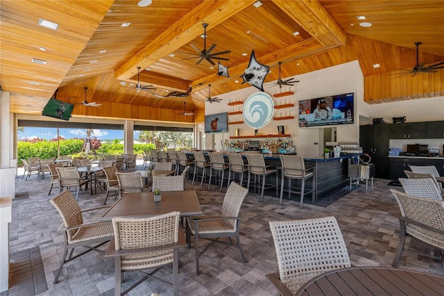 dining room featuring a community bar, ceiling fan, high vaulted ceiling, wooden ceiling, and beamed ceiling