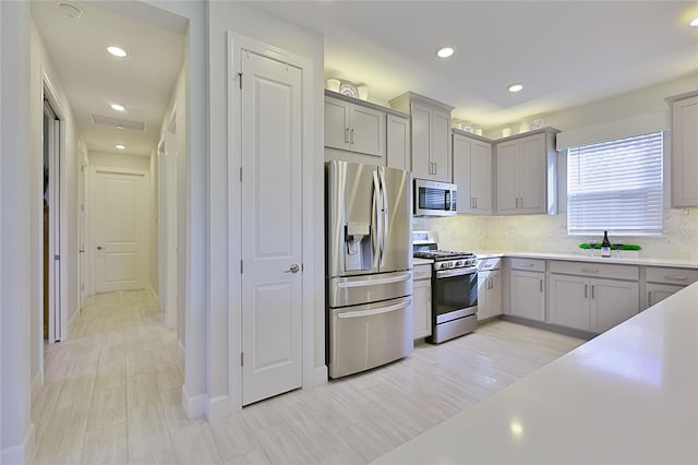 3008 Tolmino Ct, Lakewood Ranch, FL 34211 - kitchen with appliances with stainless steel finishes, gray cabinetry, and backsplash