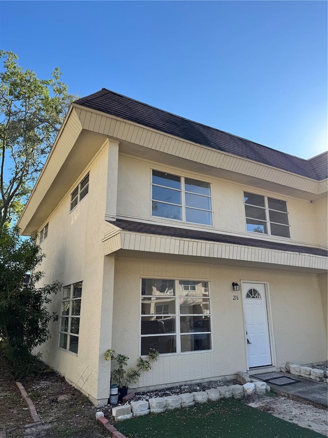 view of front of home with a shingled roof and stucco siding