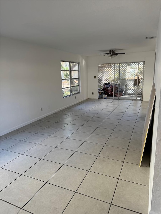 empty room with a ceiling fan, visible vents, baseboards, and light tile patterned flooring