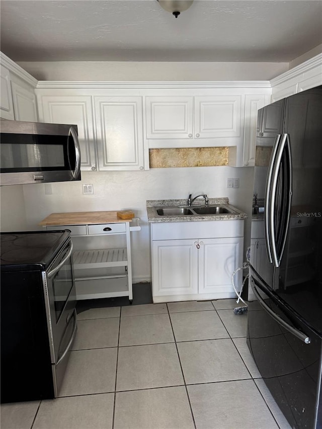 kitchen with stainless steel appliances, light countertops, white cabinetry, a sink, and light tile patterned flooring