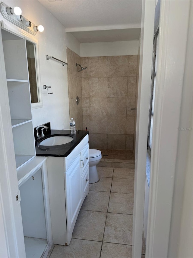 bathroom with a stall shower, vanity, toilet, and tile patterned floors