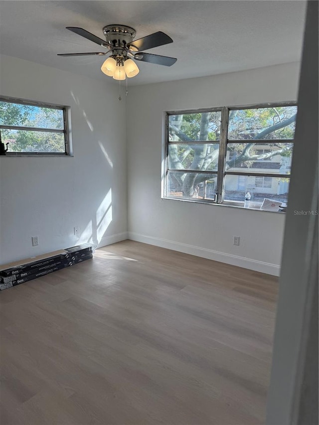 spare room with a ceiling fan, baseboards, and wood finished floors