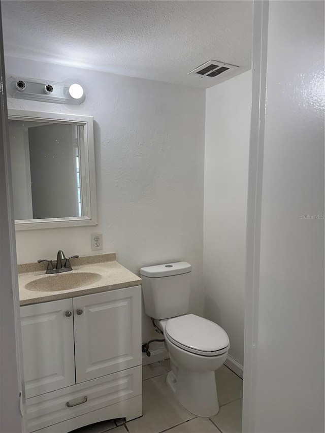 half bathroom featuring a textured ceiling, tile patterned flooring, toilet, vanity, and visible vents