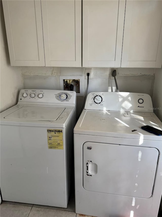 laundry area featuring light tile patterned flooring, cabinet space, and separate washer and dryer