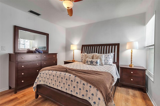 bedroom with light wood-style floors, visible vents, and a ceiling fan