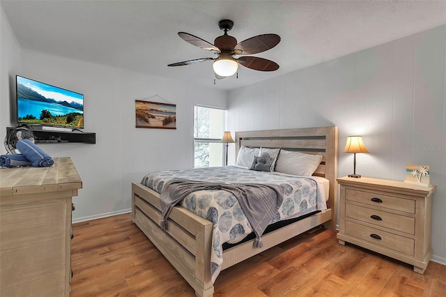 bedroom with ceiling fan, light wood-style flooring, and baseboards