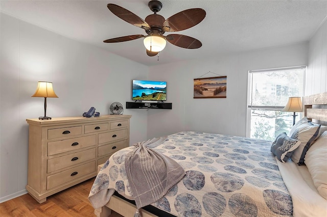 bedroom with light wood-style floors, a textured ceiling, and a ceiling fan