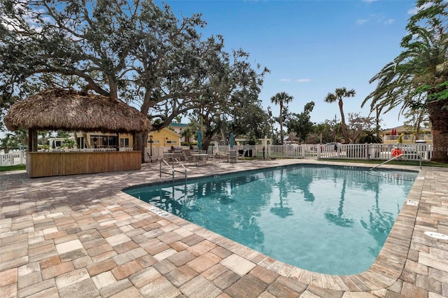 community pool featuring outdoor dry bar, a gazebo, a patio area, and fence