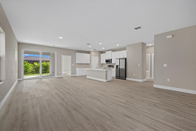 unfurnished living room featuring recessed lighting, visible vents, light wood-style flooring, and baseboards