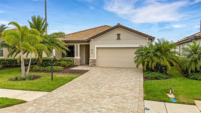 mediterranean / spanish home featuring a garage, stone siding, decorative driveway, stucco siding, and a front yard