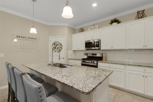 kitchen with stainless steel appliances, a sink, white cabinets, an island with sink, and pendant lighting