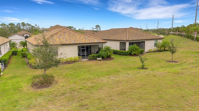 back of property featuring a tile roof, a yard, and stucco siding