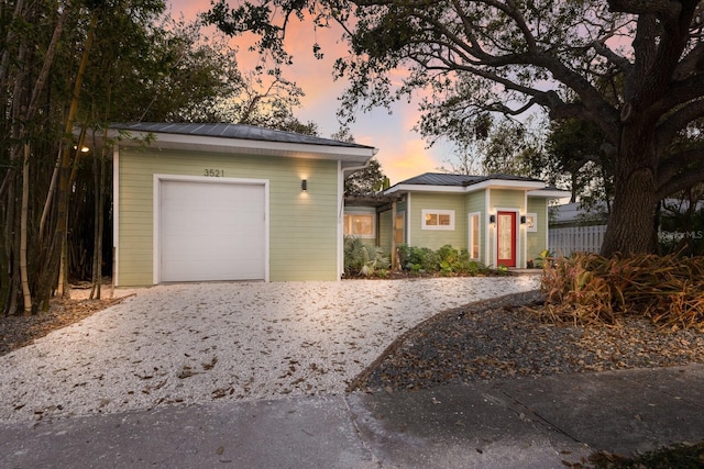 ranch-style home with a garage, a standing seam roof, metal roof, and driveway