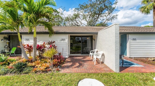 back of property with a garage, a patio area, and stucco siding