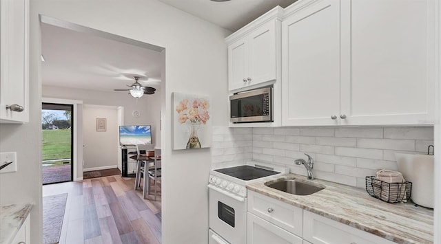 kitchen with white electric range oven, stainless steel microwave, white cabinets, a sink, and light stone countertops