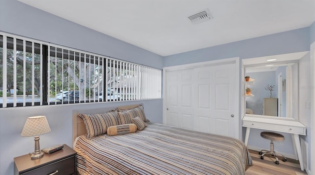 bedroom with a closet, visible vents, baseboards, and light wood finished floors