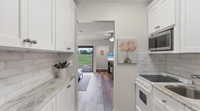 kitchen with white electric range, stainless steel microwave, and white cabinetry