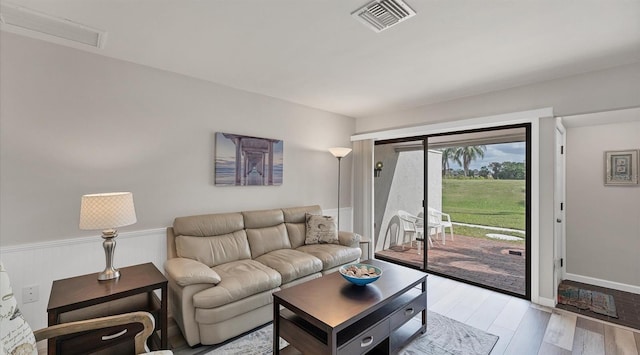 living area featuring light wood-style flooring, wainscoting, and visible vents